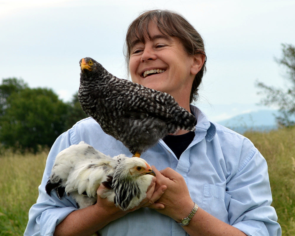 Sarah Rosedahl in a grassy field holding two chickens