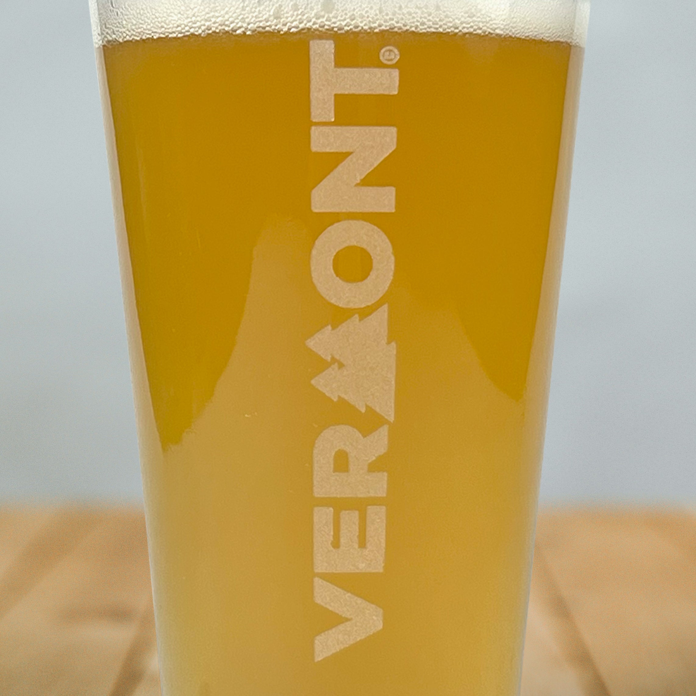 Close up of pint glass with Pining for Vermont artwork etched vertically on front of glass