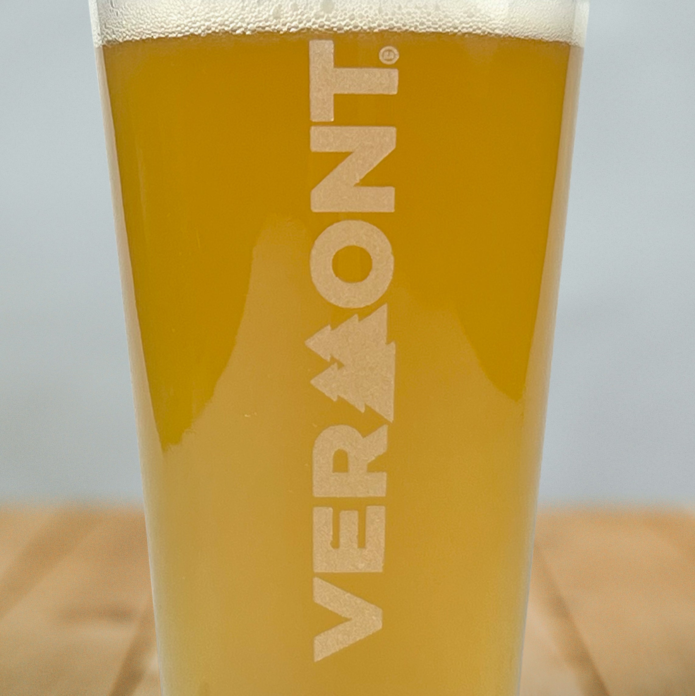 Close up of pint glass with Pining for Vermont artwork etched vertically on front of glass