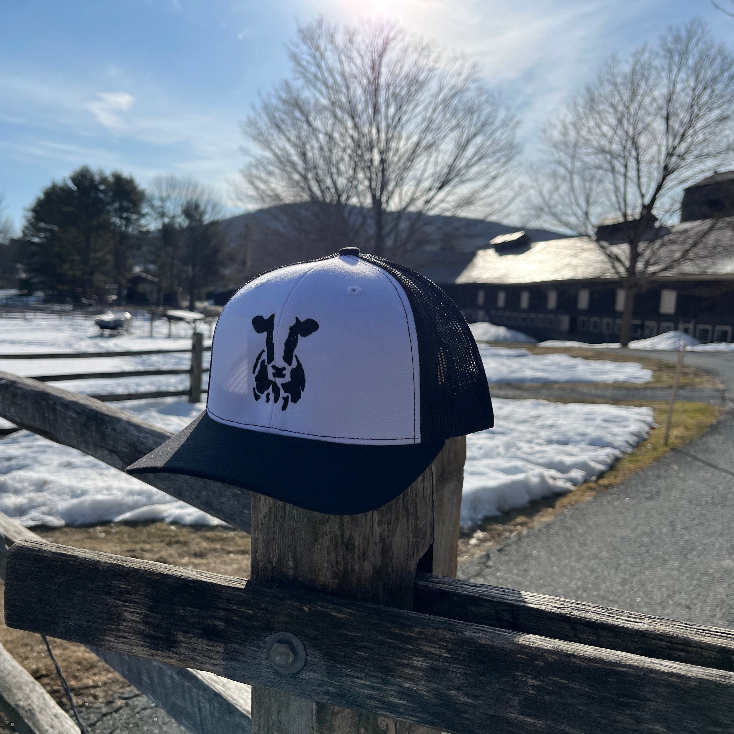 Face of Vermont trucker hat perched on a fence post with a snowy background